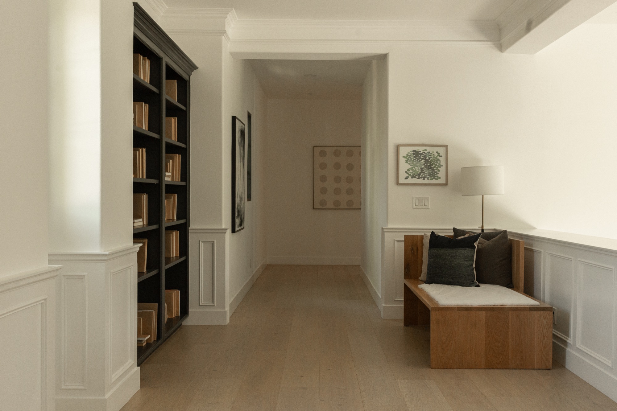 Hallway, bookshelf and window bench with framed art