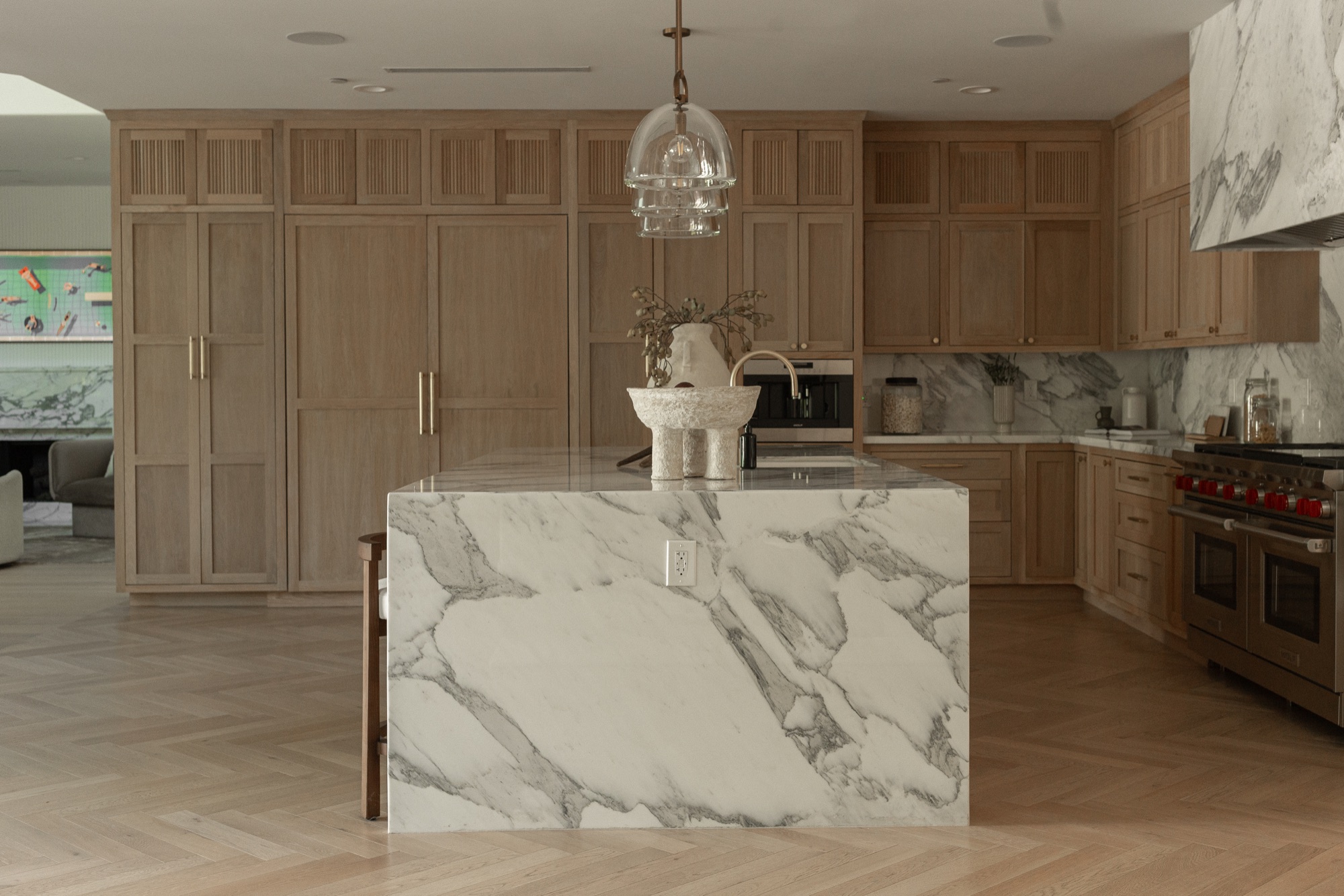 Kitchen island, marble waterfall edge with the range beyond