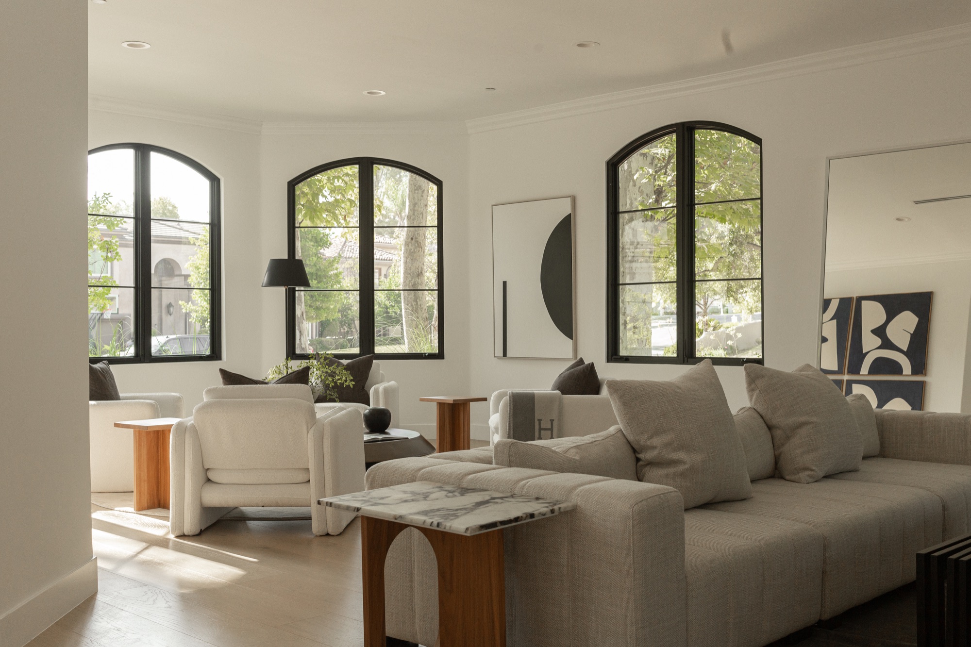 Living room, arched windows, sofa and armchairs with abstract art