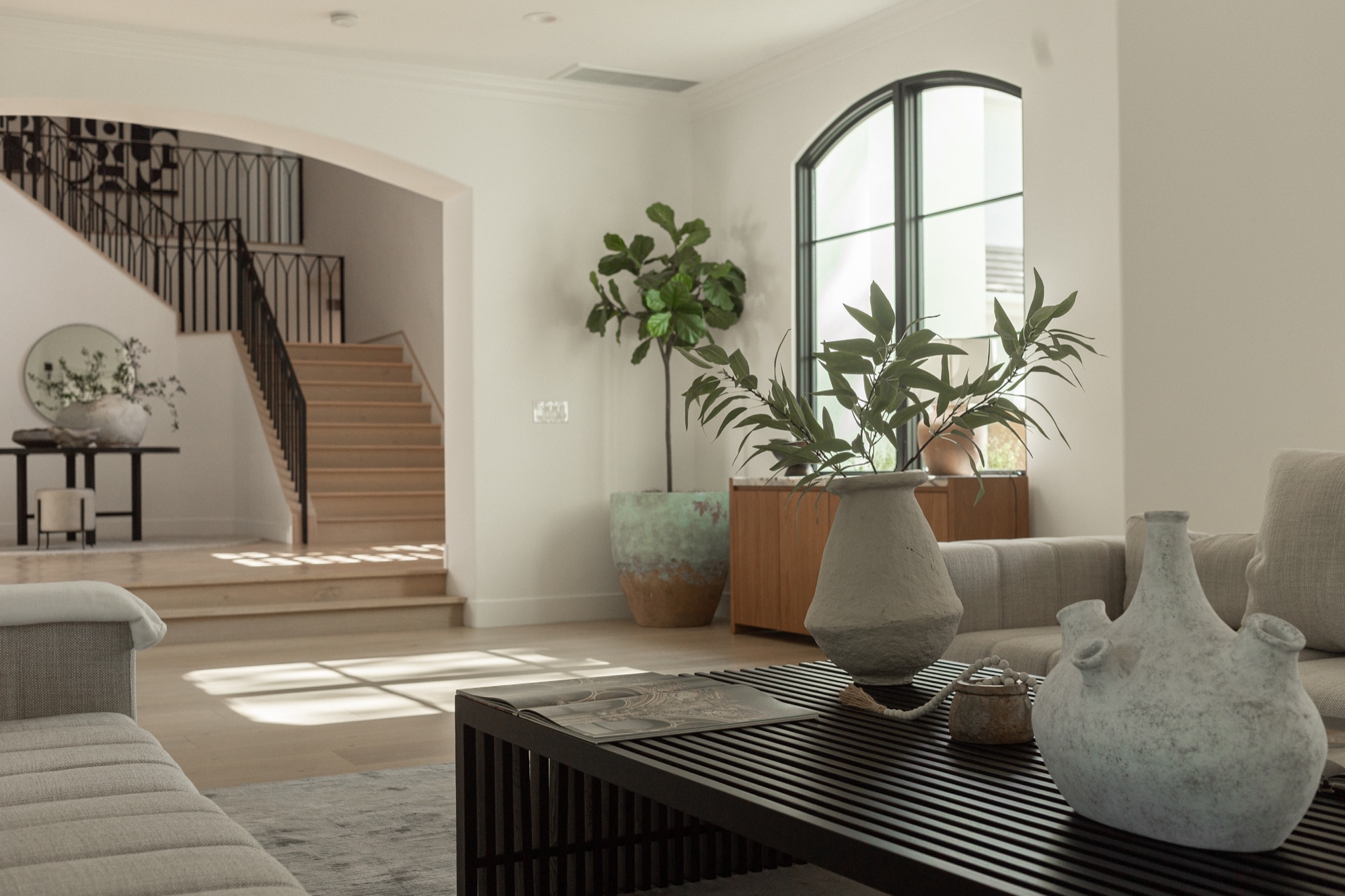 Living room, staircase view with potted plants and ceramic vessels